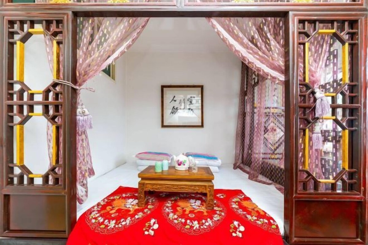 A traditional room with a bed, a small table with a teapot, and a framed picture on the wall.