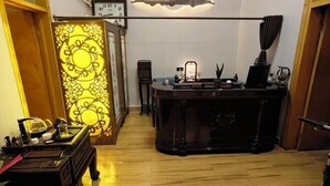 Ein traditionell eingerichteter Raum mit Holzboden, einem Schreibtisch mit Lampe, einem Stuhl und einem Wandbild.