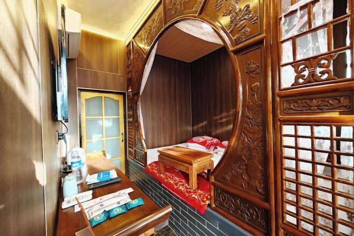 Una camera tradizionale con un letto di legno, una scrivania con una sedia, un tavolino e un paravento decorativo.