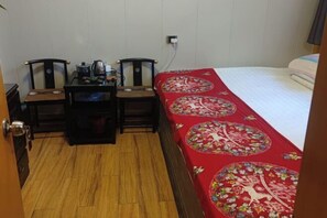 A small room with a bed, two chairs, a table, and a wooden floor. - Pingyao Xingfu House (Pingyao County)