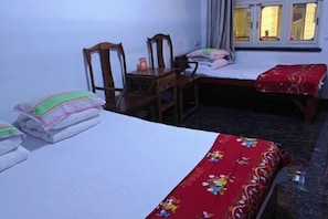 A bedroom with two beds, a wooden chair, a small table, and a window with curtains. - Pingyao Xingfu House (Pingyao County)