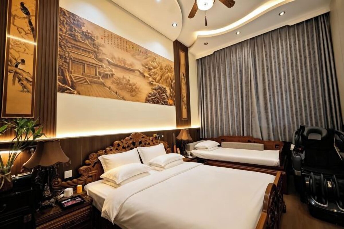 A hotel room with a large bed, a smaller bed, a desk, and a chair.