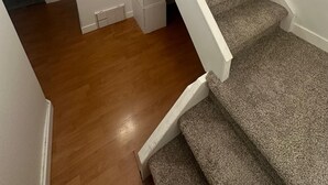 A staircase with carpeted steps and white walls, leading to a lower level.