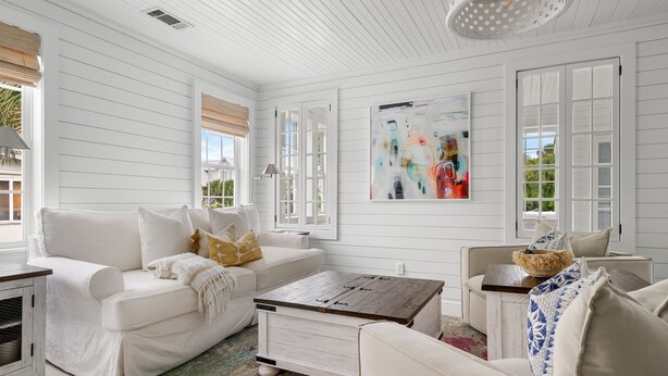 A white-walled room with a white sofa, a coffee table, and a painting on the wall. - Upstairs at Ocean | 4BR + Sunroom | Sleeps 8 (Isle of Palms)