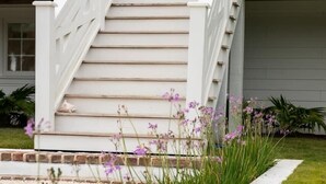 A white house with a blue door, white railings, and a front porch. - Upstairs at Ocean | 4BR + Sunroom | Sleeps 8 (Isle of Palms)
