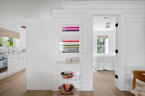 A modern kitchen with white cabinetry, a wooden floor, and a dining area with a white table and chairs.
