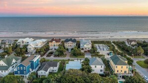 Zona residencial costera con casas, una playa y un atardecer.