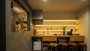 A compact kitchen with a built-in stove, a small refrigerator, and bar stools. - Kyomachi Hoshizuki (Kyoto)