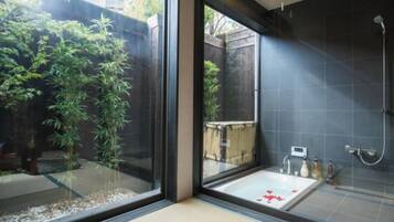 A modern bathroom with a glass partition, a bathtub, and a shower area.