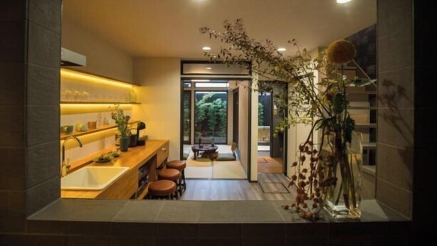A modern kitchen with a central island, a dining area with stools, and a view through a glass door to a garden. - Kyomachi Hoshizuki (Kyoto)