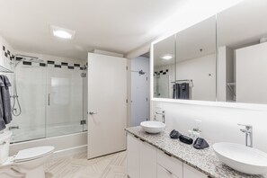 A modern bathroom with a glass-enclosed shower, a white sink, and a large mirror.
