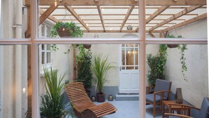 A wooden pergola with hanging plants, a wooden bench, and a table with chairs in a courtyard. - Higgihaus Apt1 36 37 Royal York Cres (Bristol)