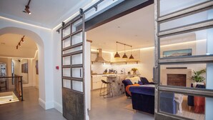 A modern kitchen with a bar area, a dining space with a sofa, and a staircase leading to another level. - Higgihaus Apt1 36 37 Royal York Cres (Bristol)