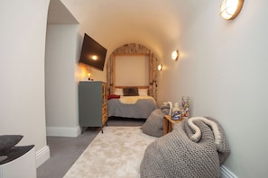 A cozy bedroom with a bed, a dresser, a TV mounted on the wall, and a small table with snacks. - Higgihaus Apt1 36 37 Royal York Cres (Bristol)