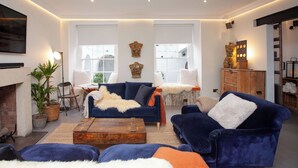 A modern living room with a blue sofa, a wooden coffee table, and a fireplace. - Higgihaus Apt1 36 37 Royal York Cres (Bristol)