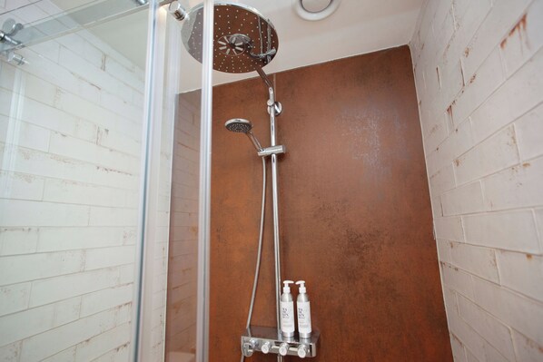 A shower with a glass enclosure, a handheld showerhead, and two bottles of shampoo. - Higgihaus Apt1 36 37 Royal York Cres (Bristol)