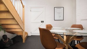 Una sala de conferències amb una taula de vidre, cadires marrons, una porta blanca i una escala.