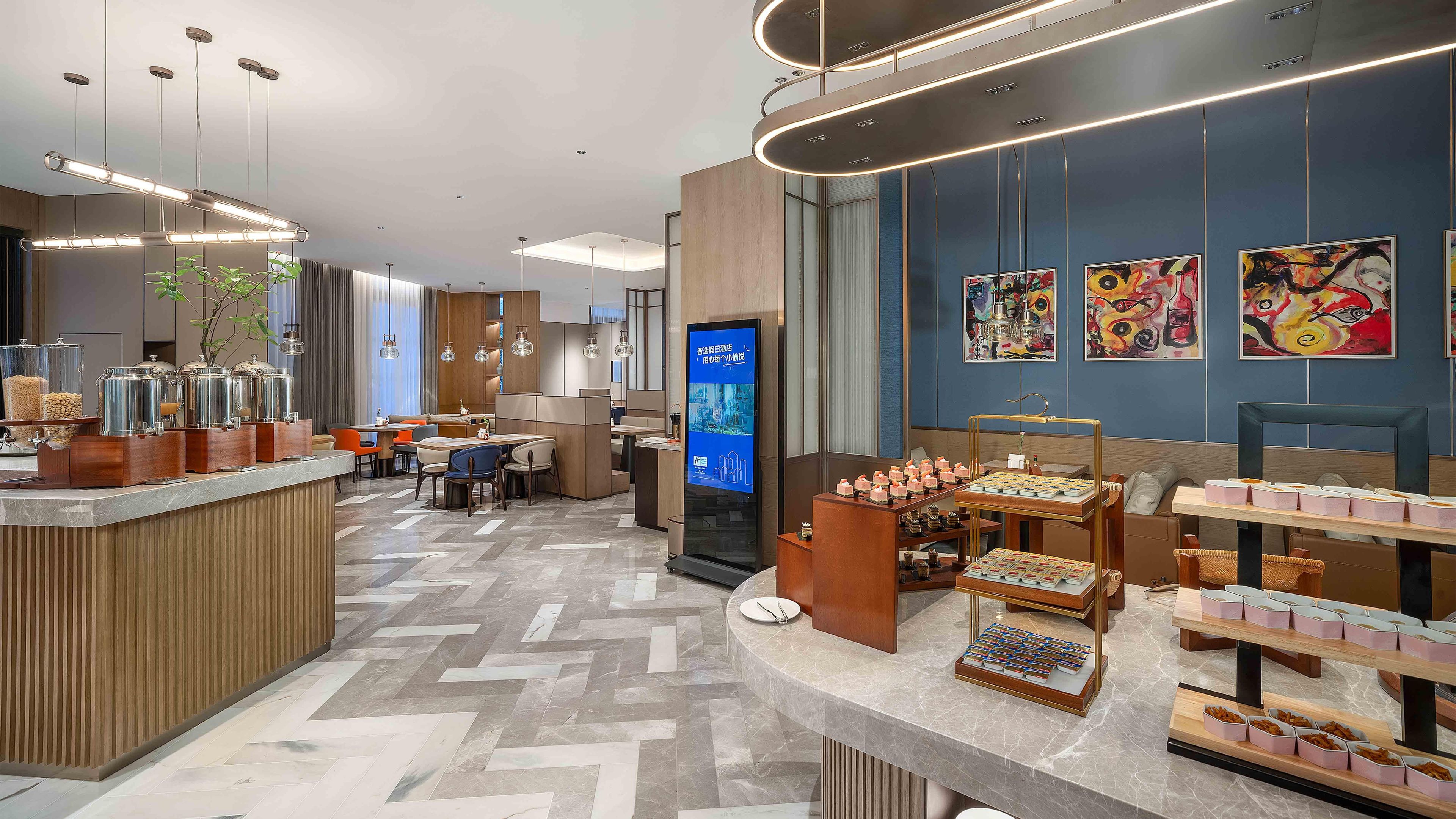 Un moderno vestíbulo de hotel con una recepción, zona de estar y un quiosco de información digital.