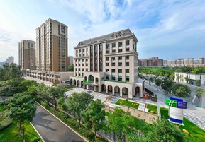 Un hotel moderno con un patio central, varios pisos y un letrero verde llamativo.