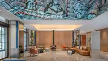 Un vestíbulo moderno con un mural grande, asientos cómodos y una chimenea central.