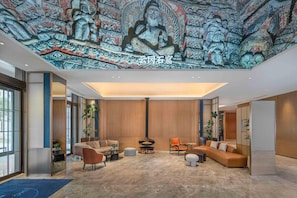 Um hall moderno com um grande mural, assentos confortáveis e uma lareira central.