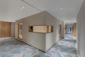 A modern hotel corridor with a geometric patterned floor, wooden paneling on the walls, and recessed ceiling lights. - Holiday Inn Express Datong Pingcheng (Datong)