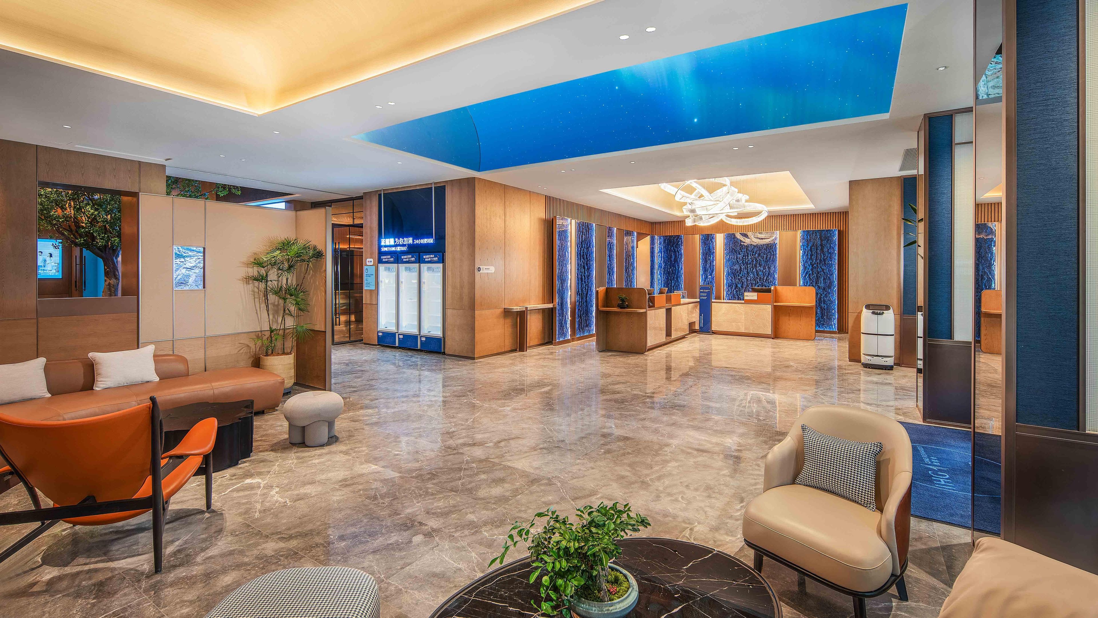 Un moderno vestíbulo de hotel con una recepción, zona de estar y un llamativo techo azul.
