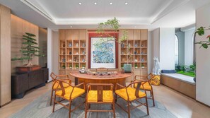 A dining area with a round wooden table, six chairs with yellow cushions, and a large wooden bookshelf filled with decorative items. - Holiday Inn Express Datong Pingcheng (Datong)