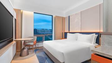 Una habitación de hotel moderna con una cama grande, un escritorio, una silla y un televisor.