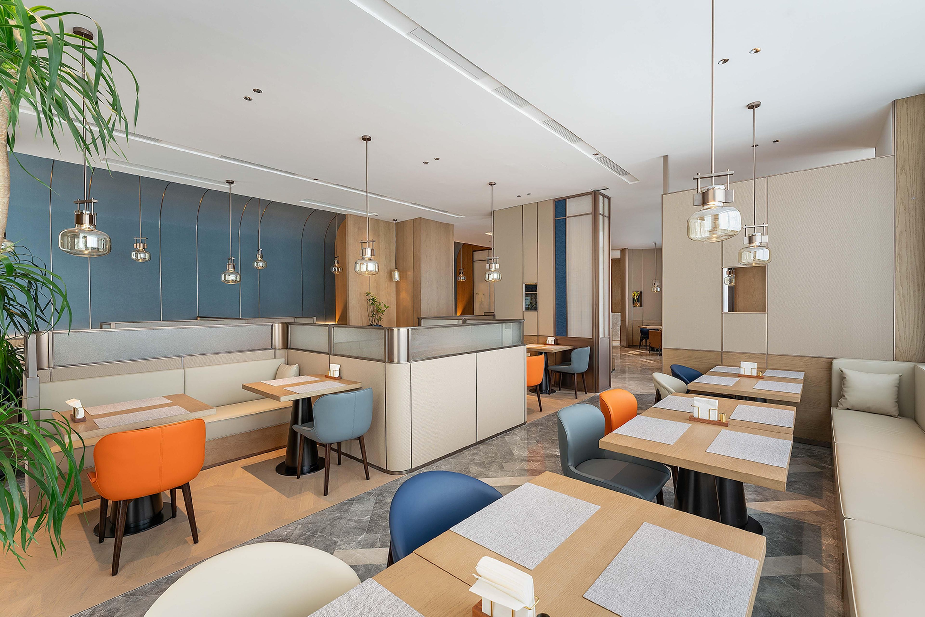 Un restaurante moderno con cabinas, mesas y lámparas colgantes.