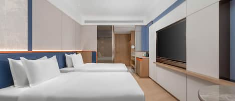 Habitación de hotel con dos camas, televisión y una kitchenette pequeña.