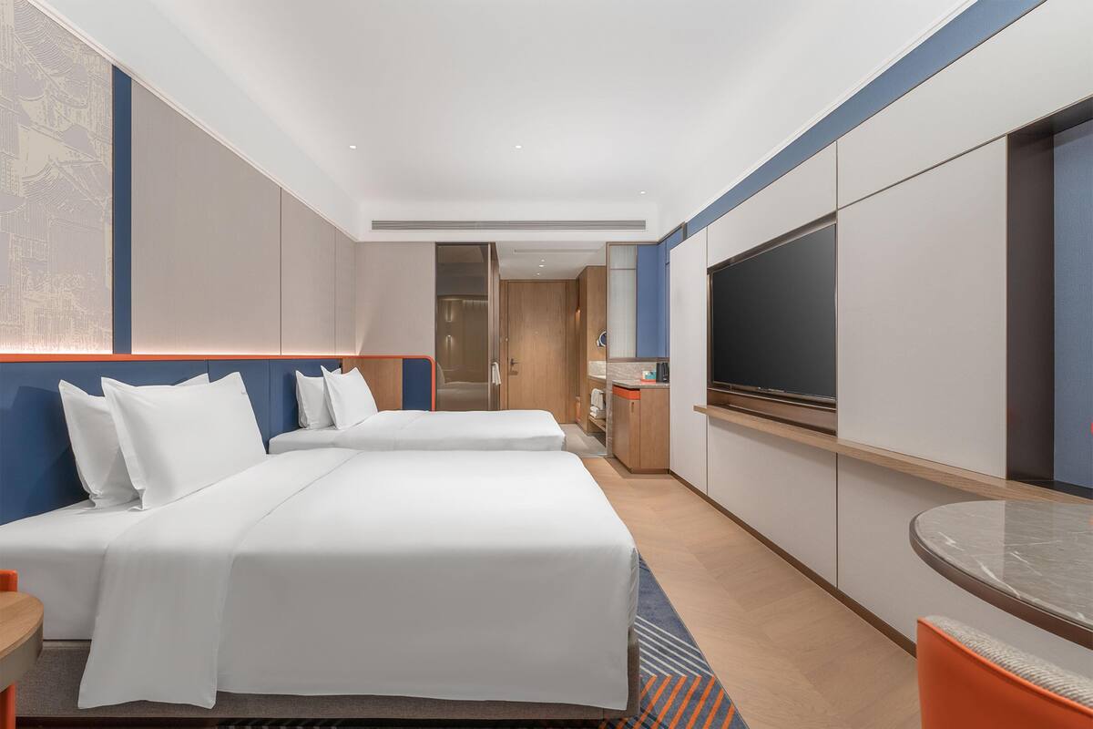 Hotellihuone, jossa on kaksi sänkyä, televisio, työpöytä ja kylpyhuone.