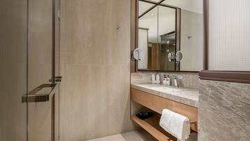 Une salle de bain moderne avec une douche à l’italienne en verre, un meuble-lavabo en bois avec un plan de travail en marbre et un grand miroir au-dessus du lavabo.