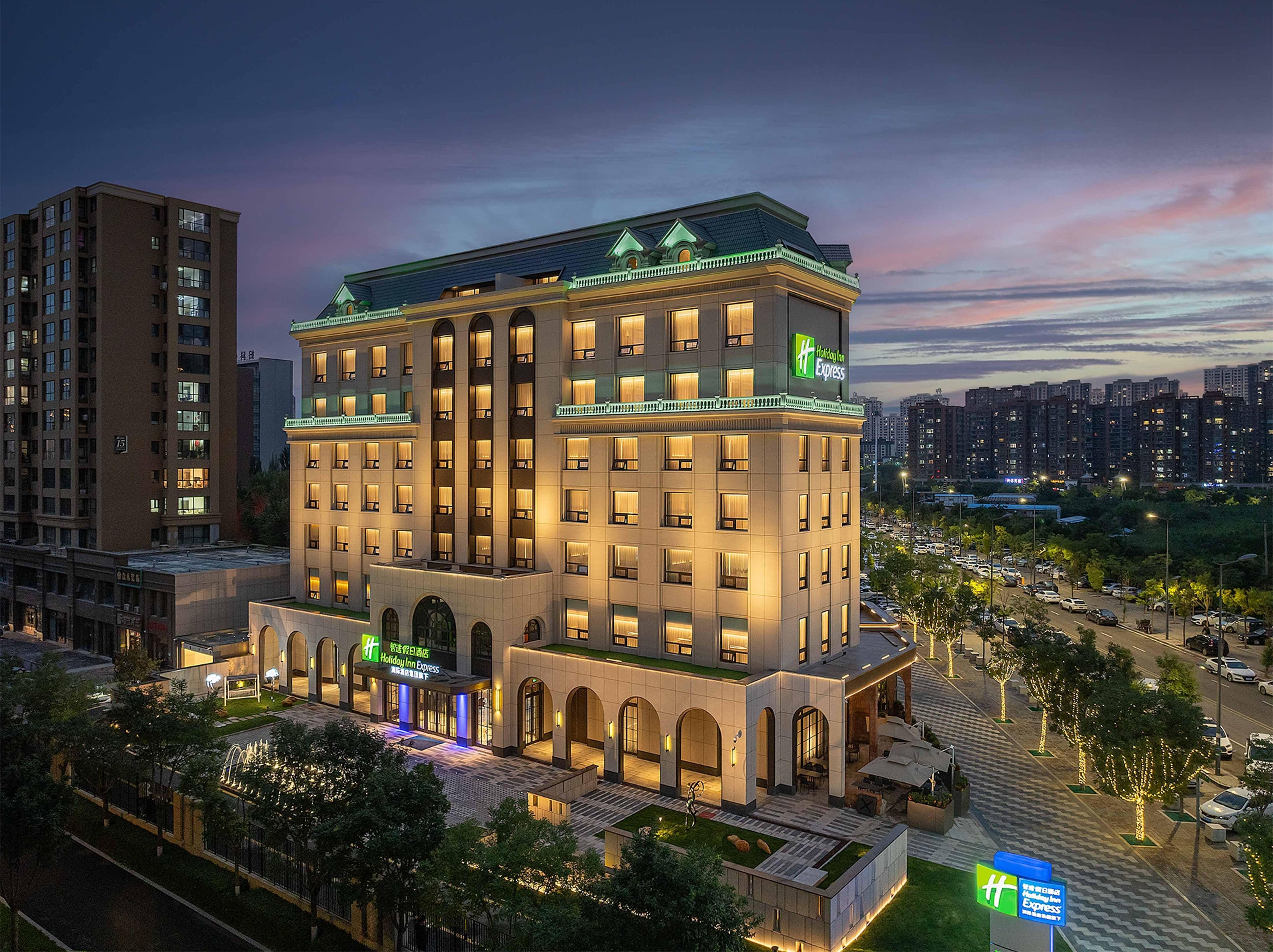 A multi-story Holiday Inn Express hotel with a modern design, featuring a prominent entrance and a rooftop terrace.