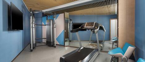 A modern fitness center with a treadmill, weight machines, and exercise chairs.