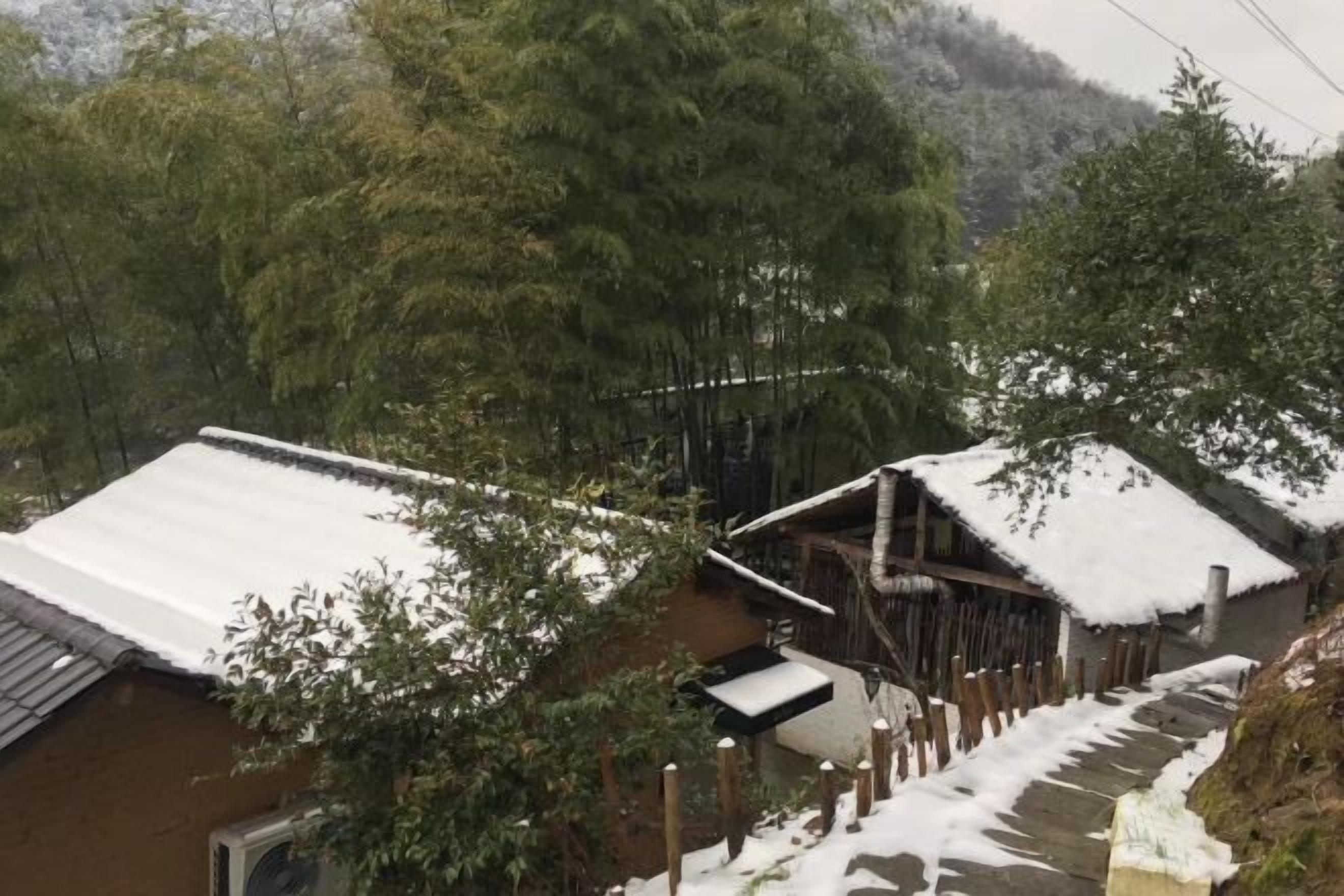 A traditional wooden house with a snow-covered roof and a wooden staircase leading to a wooden deck.