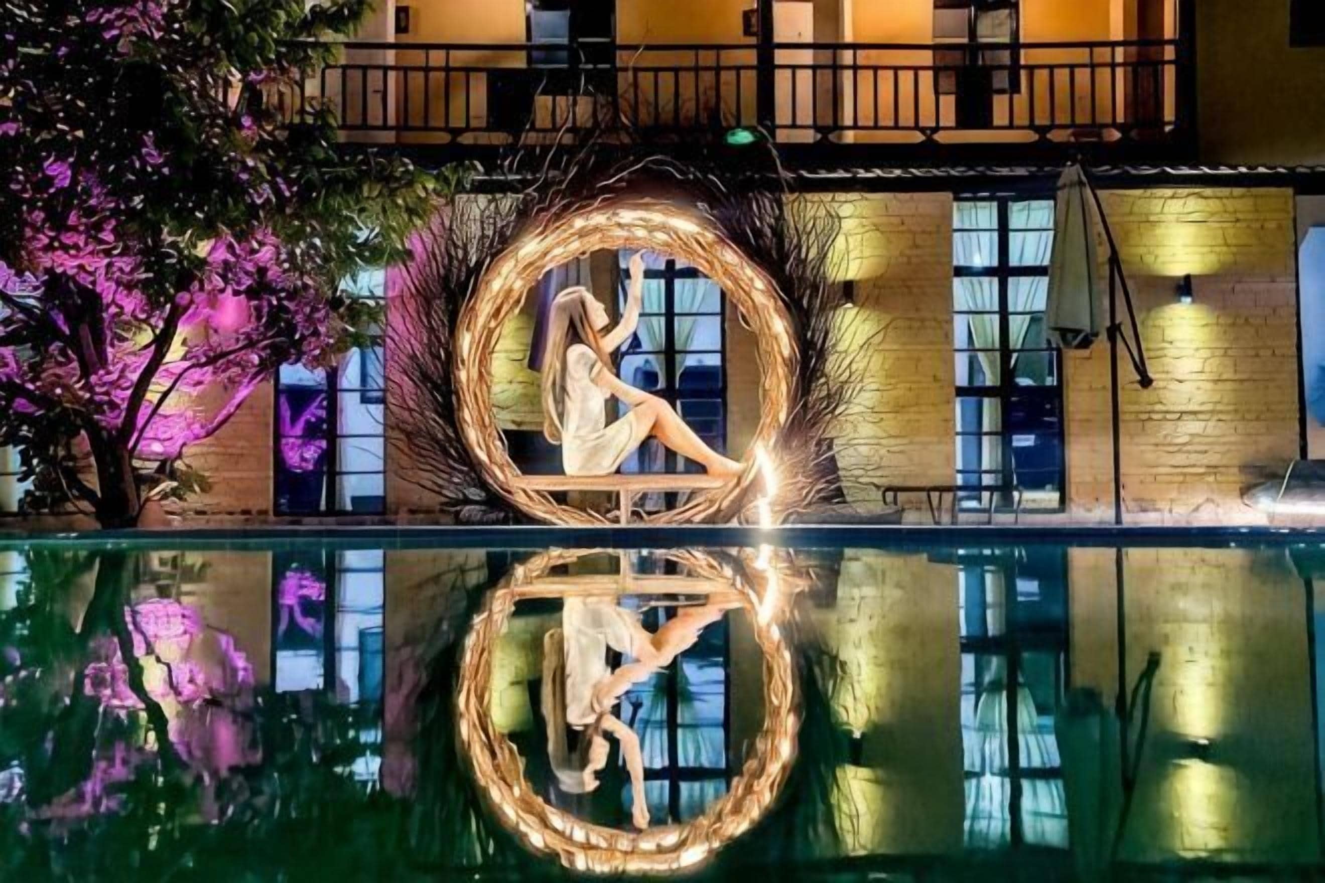 Une piscine avec un luminaire circulaire et le reflet d’une personne.