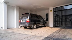 A car parked inside a garage with a black gate. - Hotel O Mahagoni House Syariah (Bogor)