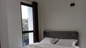 A bedroom with a large window, a bed with white bedding, and a dark headboard. - Hotel O Mahagoni House Syariah (Bogor)