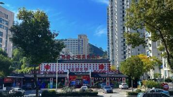 A street view with a row of shops, a pedestrian crossing, and tall buildings in the background.
