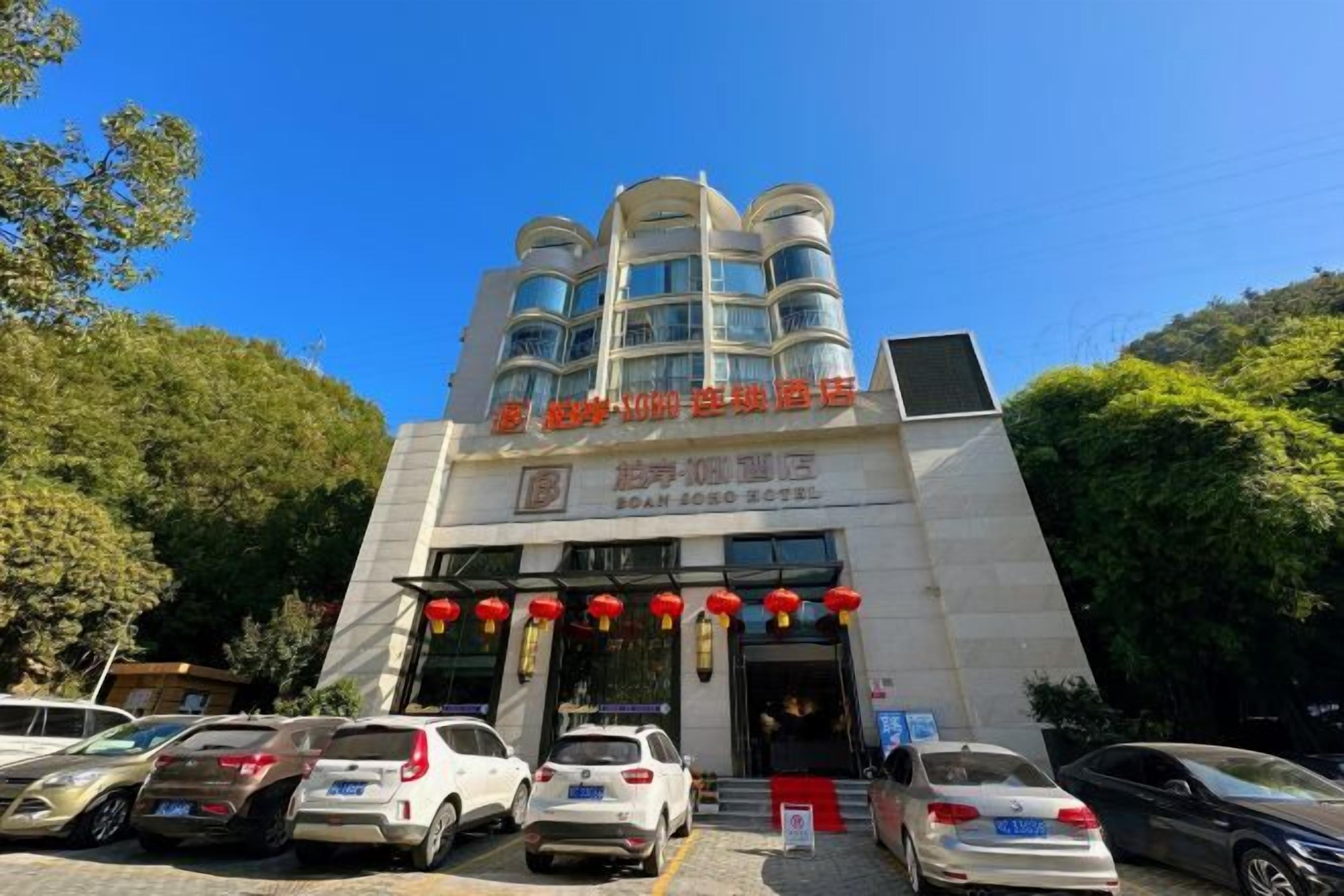 A hotel with a modern architectural design, featuring a prominent entrance with a red awning and multiple balconies.