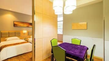 Una habitación de hotel con una cama, una mesa de comedor con sillas y un cuadro en la pared.