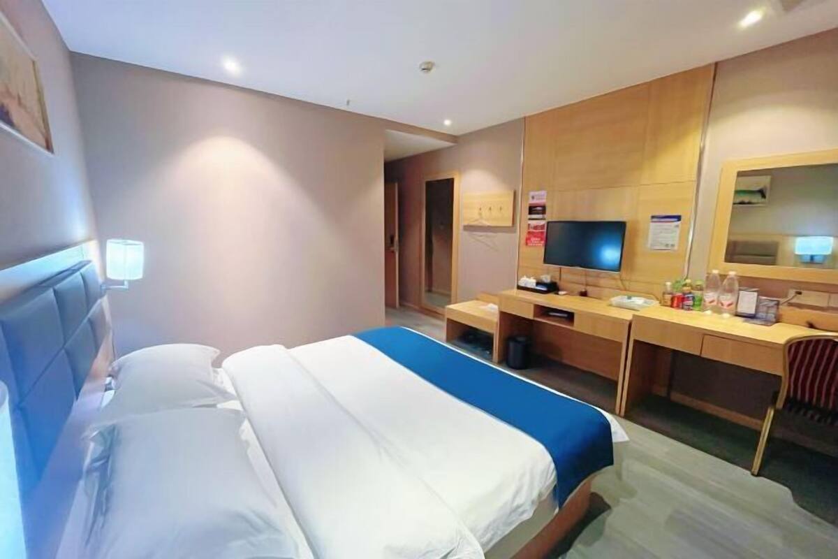 Une chambre d’hôtel avec deux lits, un bureau, une télévision et un miroir.