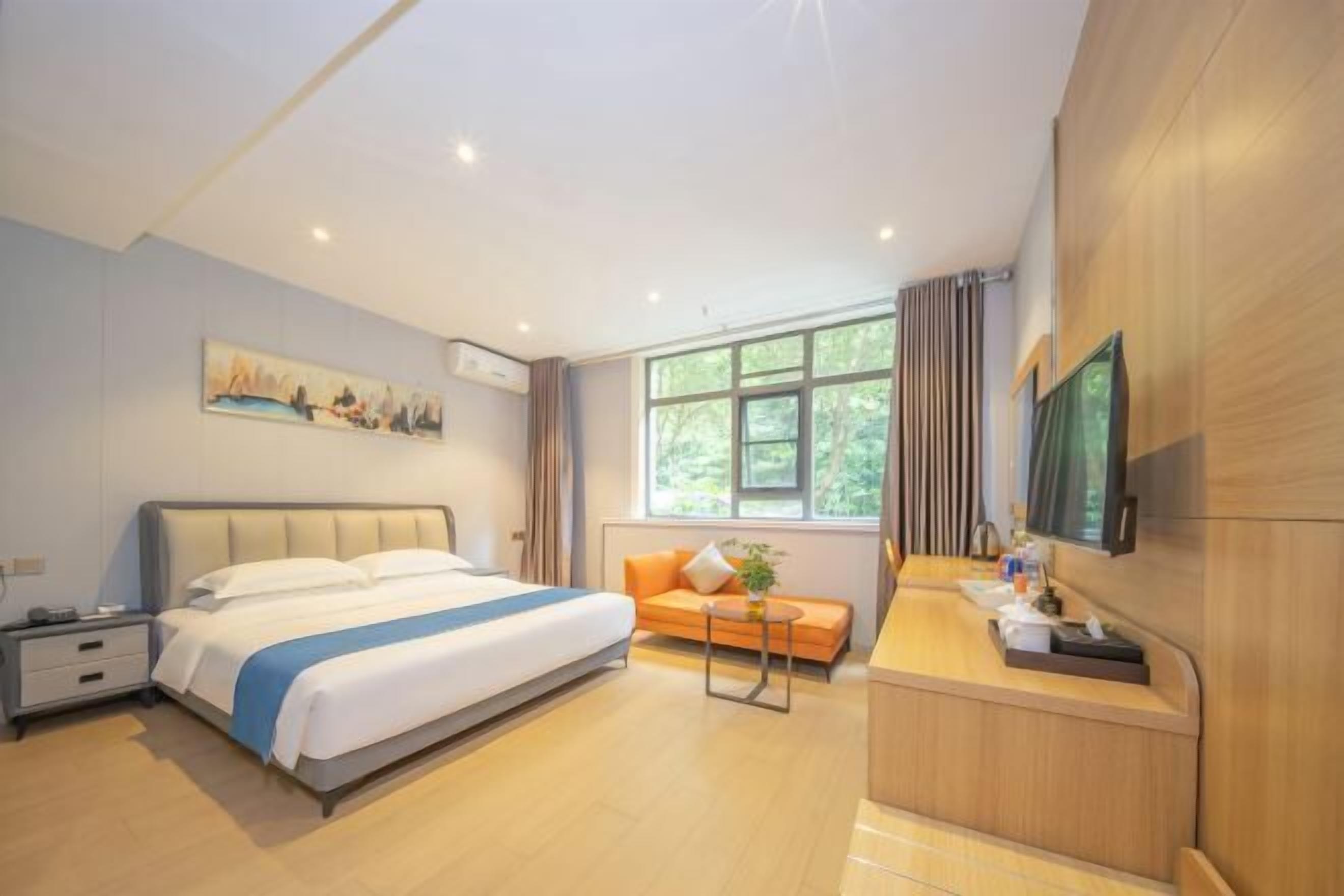 Habitación de hotel con cama, escritorio, sofá, ventana y un cuadro en la pared.
