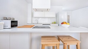 Una cocina moderna con armarios blancos, microondas, fregadero y frutero.