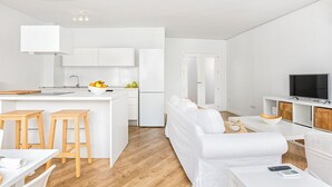 Un espacio habitable moderno con una decoración blanca, que incluye una cocina, comedor y zona de estar.