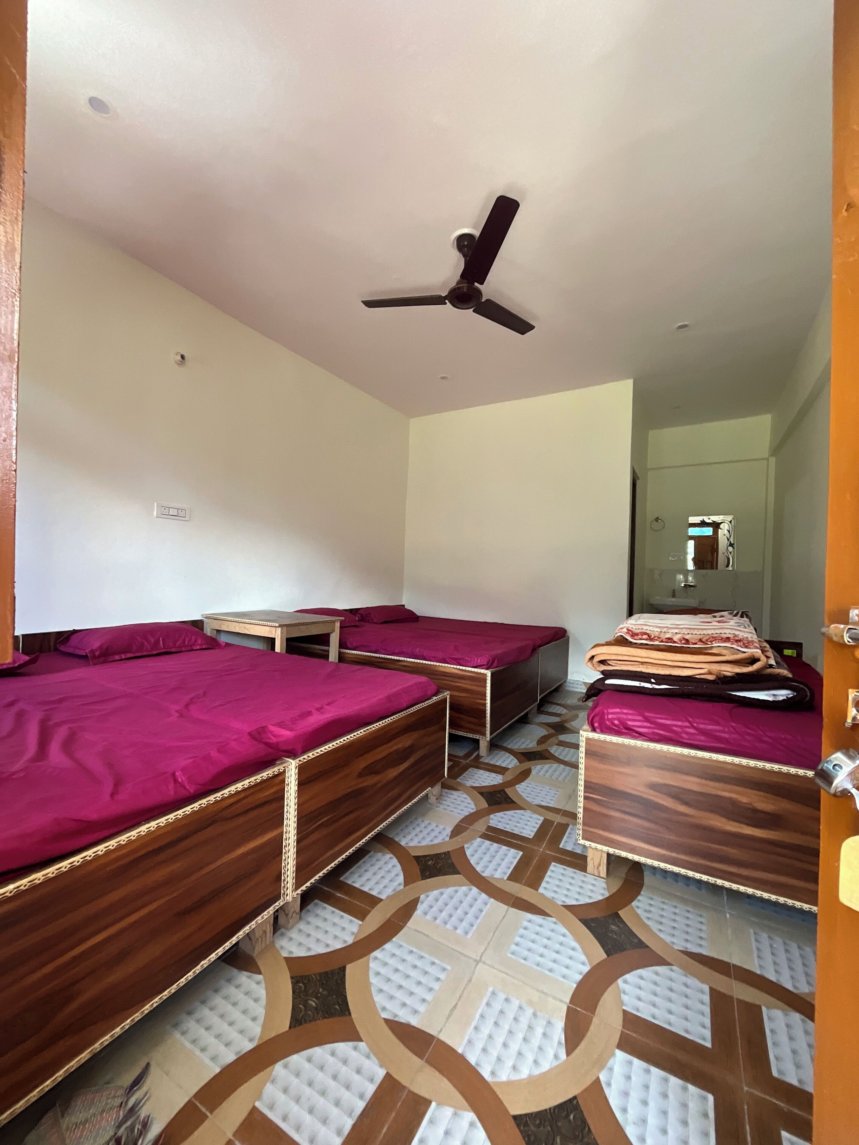 A room with three wooden beds, a ceiling fan, and a patterned floor.