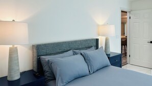 Un dormitorio ordenado con cama, dos mesitas de noche y lámparas.