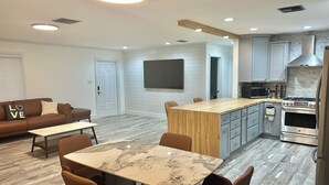 Una cocina moderna con una isla de madera, electrodomésticos de acero inoxidable y un comedor con mesa de mármol.