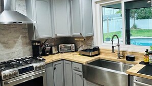 Una cocina moderna con armarios grises, una estufa de acero inoxidable y una ventana con vista a un jardín.